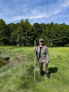A woman standing in a saltmarsh near a creek.