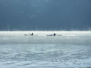 Mist rises from the waters of Lulu Lake as two kayakers paddle by.