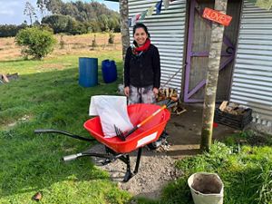 A person standing next to a red wheelbarrow.