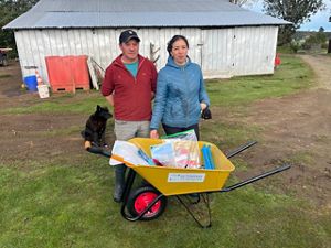 A man and a woman with a yellow wheelbarrow filled with supplies to harvest sphagnum moss.