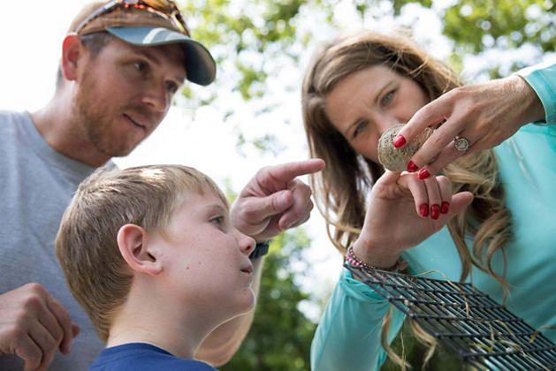 Three people look at something found in nature.