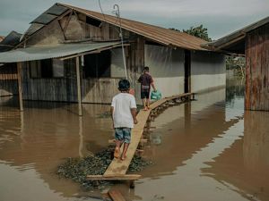  Dos niños utilizan una pasarela de madera para cruzar el agua que rodea las casas después de que las fuertes lluvias provocaran el desbordamiento de la laguna Yarinacocha.