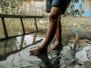 Una persona camina descalza por las aguas de la inundación.