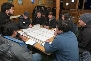 a group of diverse people sits around a table and discusses sphagnum moss harvesting.