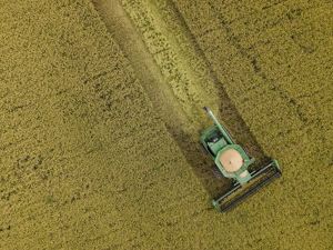 Aerial view looking straight down at a green tractor plowing an agricultural field.