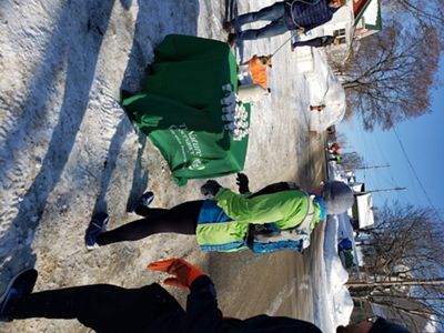 A runner stops at a table to take a small cup of maple syrup.