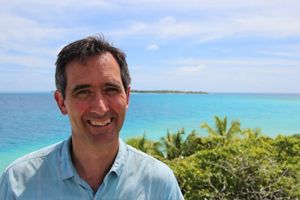 Headshot of Mark Spalding with a tropical body of water in the background