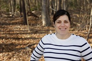 Una mujer se encuentra frente a un fondo de bosque marrón borroso.