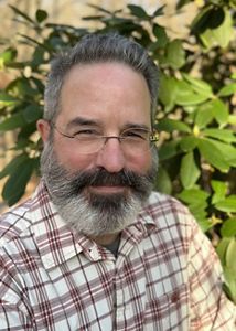 A man with a beard and glasses smiles at the camera.