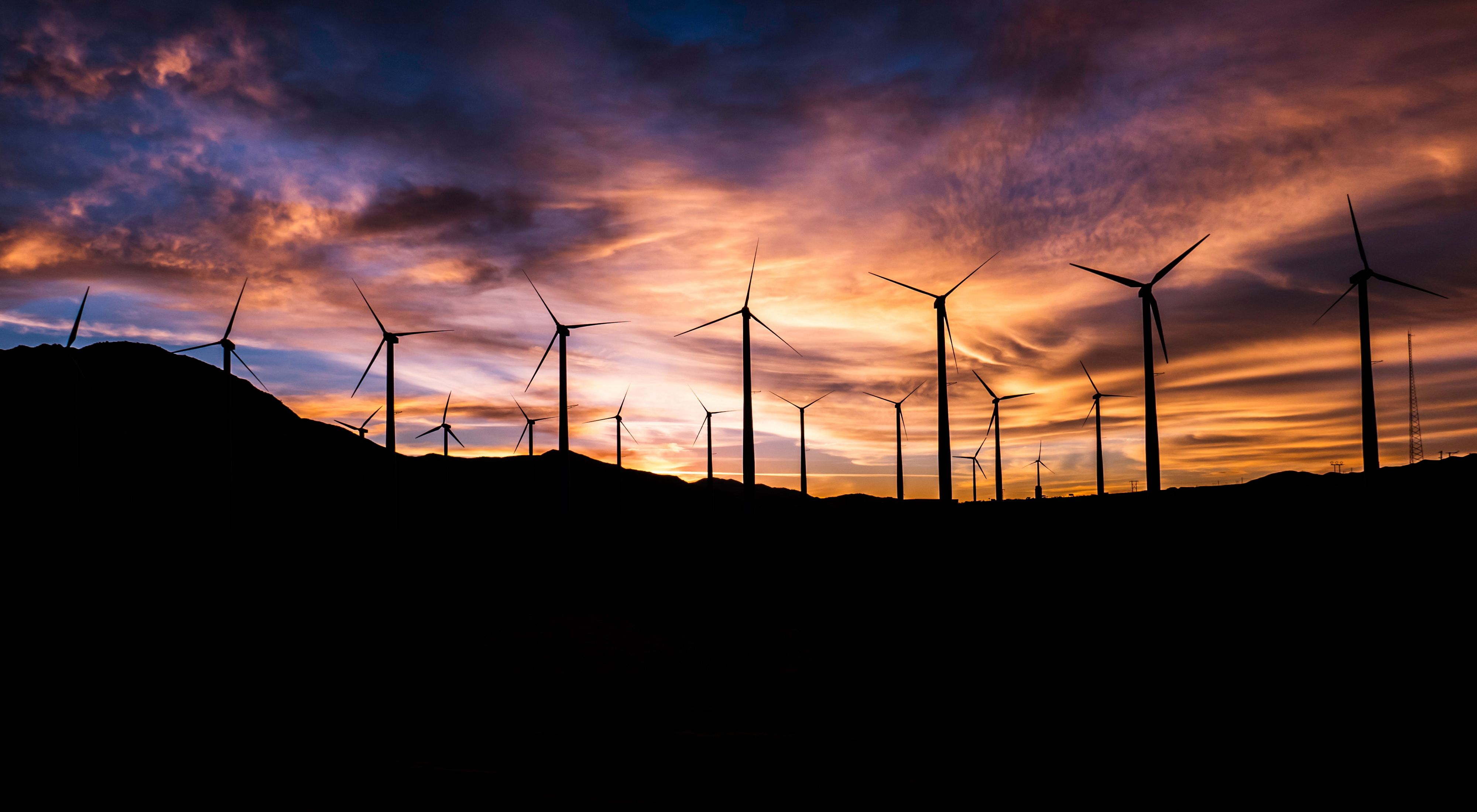Wind turbines silhouetted against the sky at sunset.