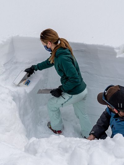 Two people taking snow samples in a dug-out snow pit. 