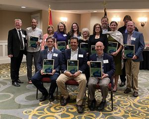 Geoff Smith stands with fellow Visionary Award recipients holding plaques during a Gulf of Maine Council on the Marine Environment awards ceremony indoors.