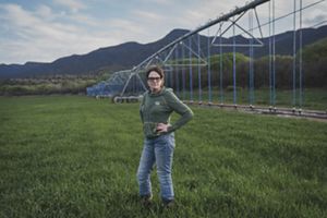 Woman standing in green jacket in an agriculture field.