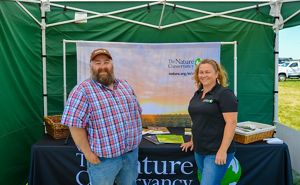Joel Leland and Rebecca McNitt of the TNC Soil Health team stand at a booth at a tradeshow in Michigan. 