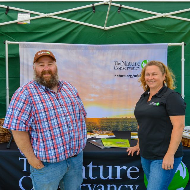 Joel Leland and Rebecca McNitt of the TNC Soil Health team stand at a booth at a tradeshow in Michigan. 