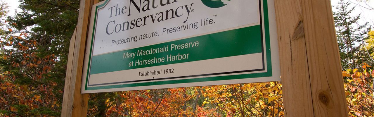 Mary Macdonald Preserve signage in front of autumn-colored trees. The preserve is located in the Keweenaw Peninsula in Michigan's Upper Peninsula. 