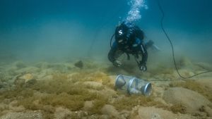 A diver underwater monitoring a rusty crayfish trap.