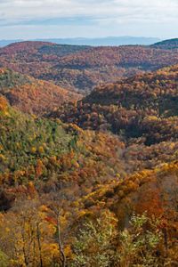 Colorful mountains in the fall with a blue gray sky above them.