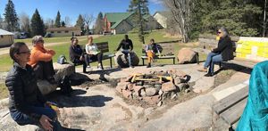 a few people sit around a fire pit on a sunny day