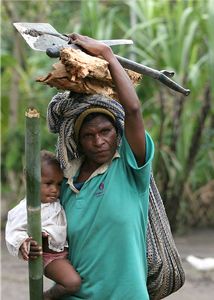 A woman holding a baby and firewood.