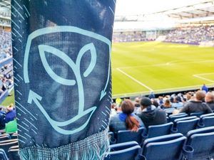 A scarf with the Sporting Sustainability logo with the soccer field in the background.