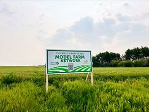 A sign posted in an agriculture field stating that it is part of the Model Farm Network. 