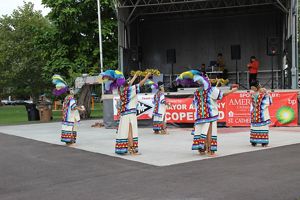 Personas con vestimenta colorida y alusivas a las culturas indígenas mexicanas realizan un baile en el festival de la monarca.