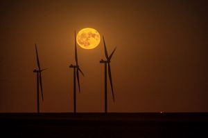 The full moon rises above windmills. 