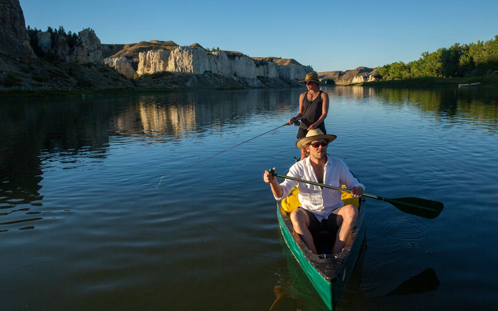 
                
                  Gone Fishing Paul Kupfer paddles while Blakeley Adkins fishes off the side of their canoe as they enter the White Cliffs section of the Upper Missouri River, a popular fly fishing spot.
                  © Louise Johns
                
              