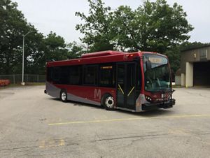 A red city bus parked in a parking lot.