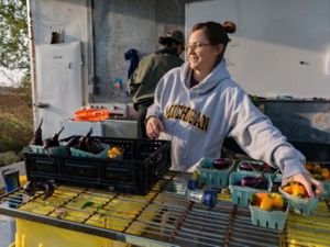 A woman smiles as she reaches for freshly picked produce in an open kitchen.