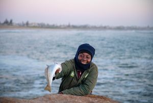 A woman holds up a fish.