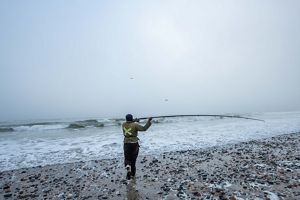 A fisherwoman casts into the sea.