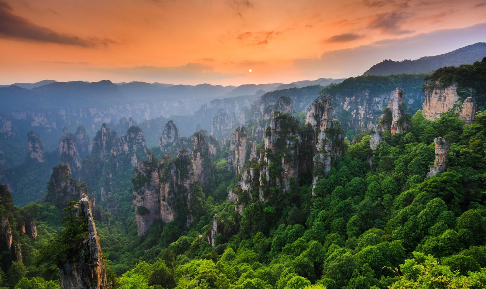 mountainous view of rock and greenery against a sunset sky