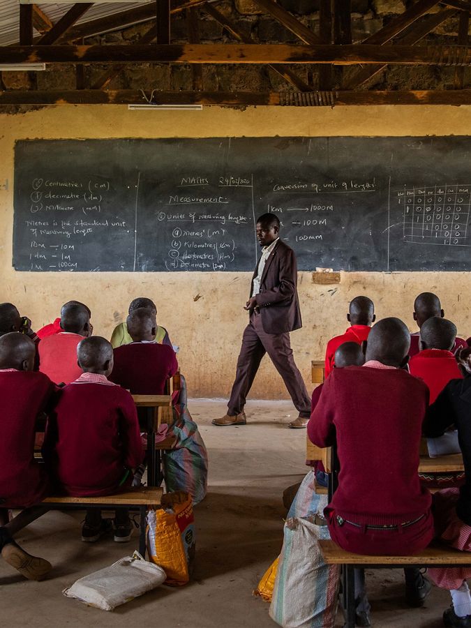 a man stands at the front of a classroom of children