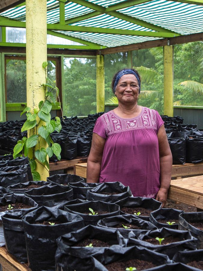 a smiling woman stands in plant nursery     