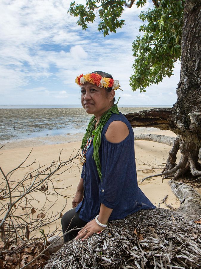 a woman sits along eroding coastline