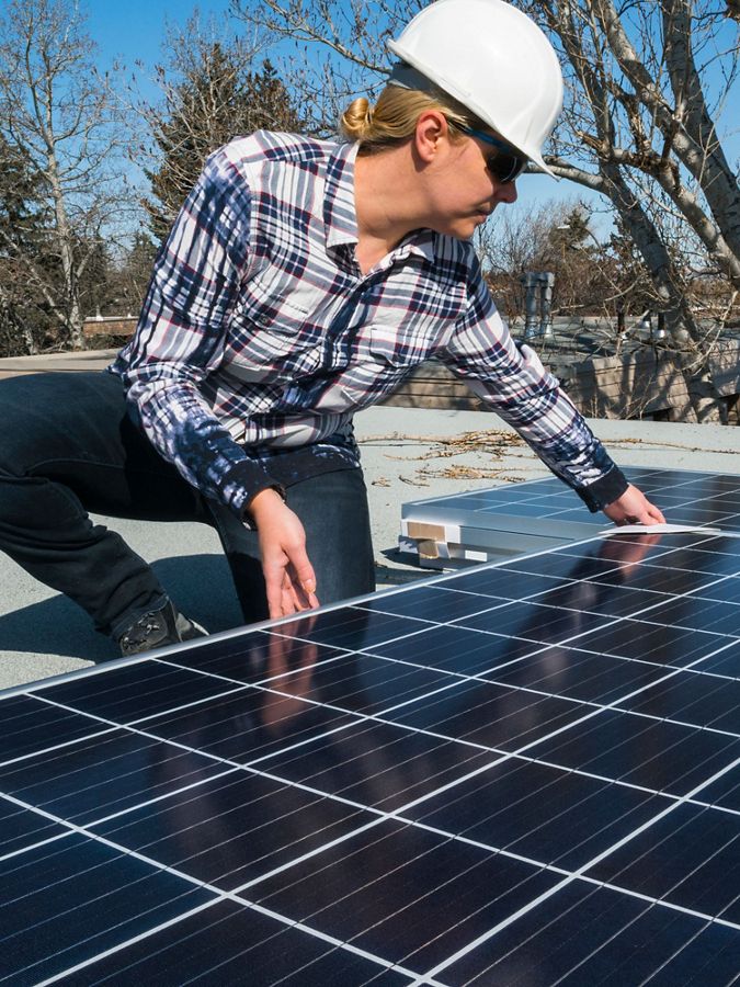 woman installs solar panel on a roof