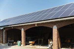 A view of a solar panel array on top of a brick roof with blue sky in background.