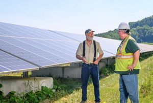 Landscape with two people in front of solar panels. 