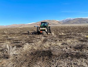 A tractor rolls across a landscape of dead grass.