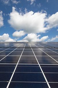 Solar panels against a cloudy blue sky.