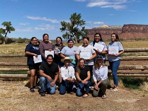 NATURE Program interns smiling while holding certificates while out in nature.