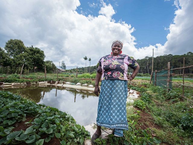 Elena stands in front of the water pan she received from the Tana-Nairobi Water Fund.