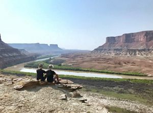 Chad and partner Matthew sit overlooking rocky landscape of Utah's Green River with Canyonlands National Park in distance.