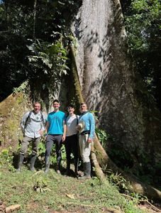 Chad Duplain with partner Matthew stand with two men in front of large tree in the Peruvian Amazon.
