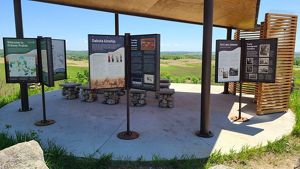 A shaded circular pavilion with three signage stanchions and rock seating.