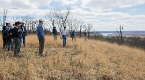 Group of people atop a bluff taking in a view overlooking a river below.