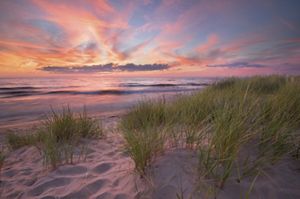 A colorful sunset over the sandy shore of Oval Beach in Saugatuck, Michigan.