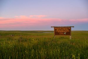 A sunset over a sign in the prairie.